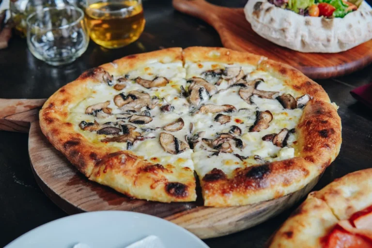 Mushroom pizza with melted cheese on a wooden plate