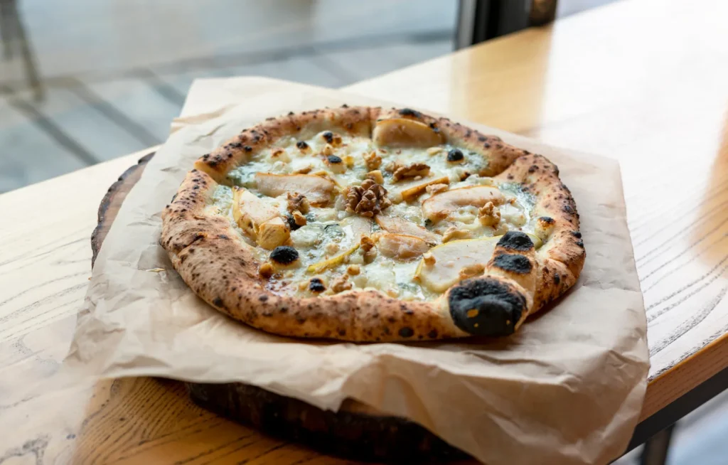 Pizza with pear, blue cheese and walnuts on a wooden board