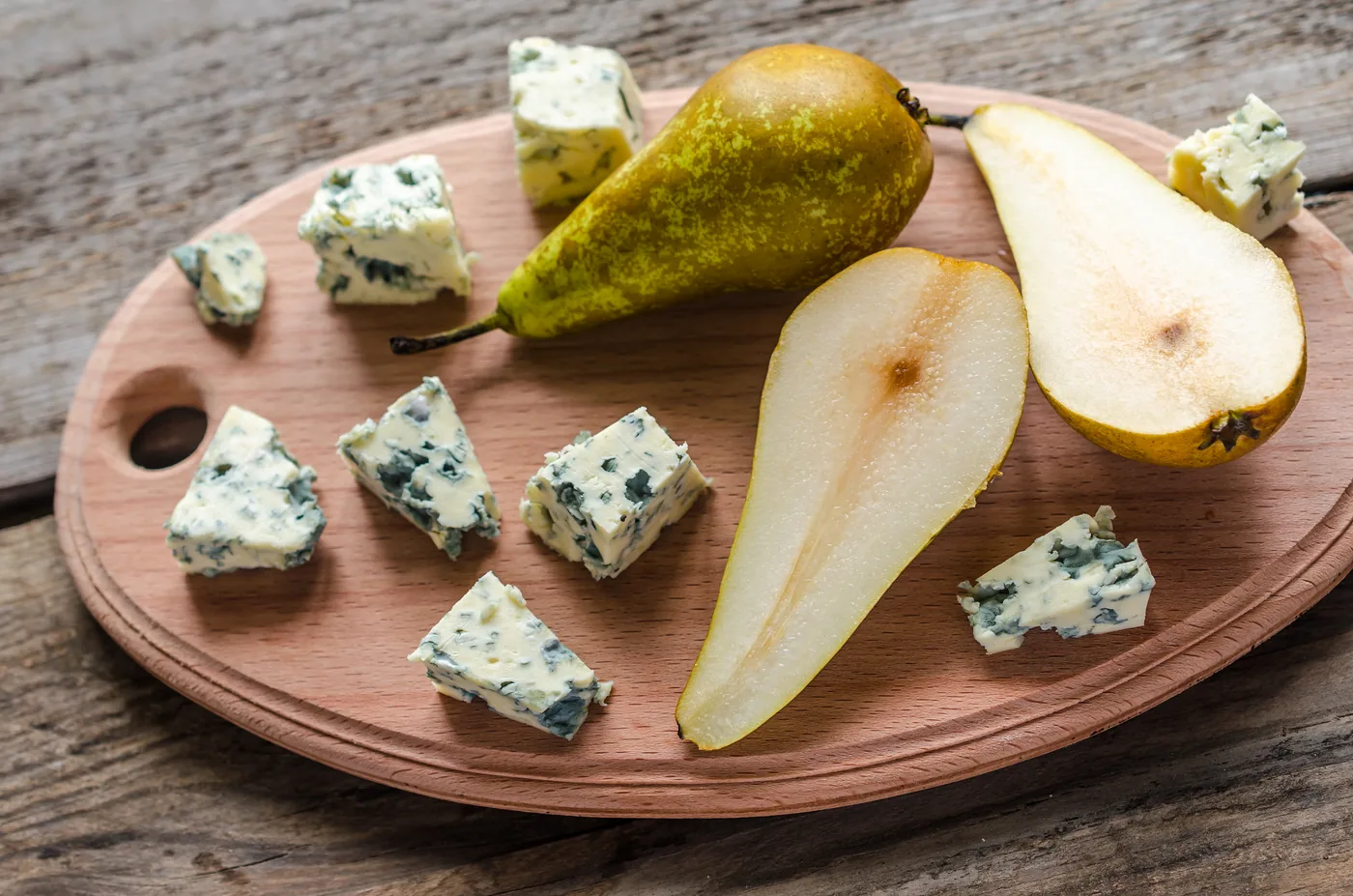 Fresh pear halves and pieces of Gorgonzola on a wooden board